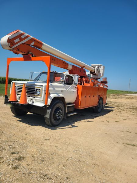 Orange and white bucket truck parked on a gravel lot