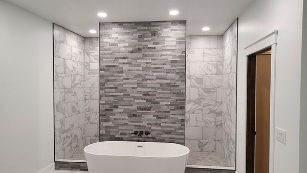 Bathroom with recessed lights over a freestanding tub and tile wall