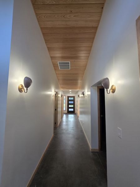 Hallway with wall sconces and a wood ceiling