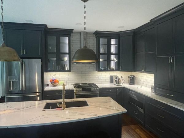 Dark-cabinet kitchen with pendant lights over the island and under-cabinet lighting