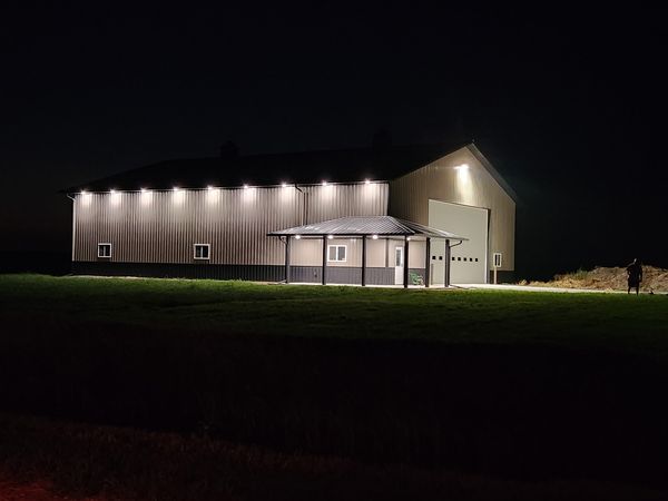 Pole barn building at night lit by exterior wall lights