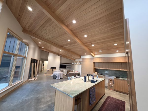 Open kitchen with recessed lights in a vaulted wood ceiling